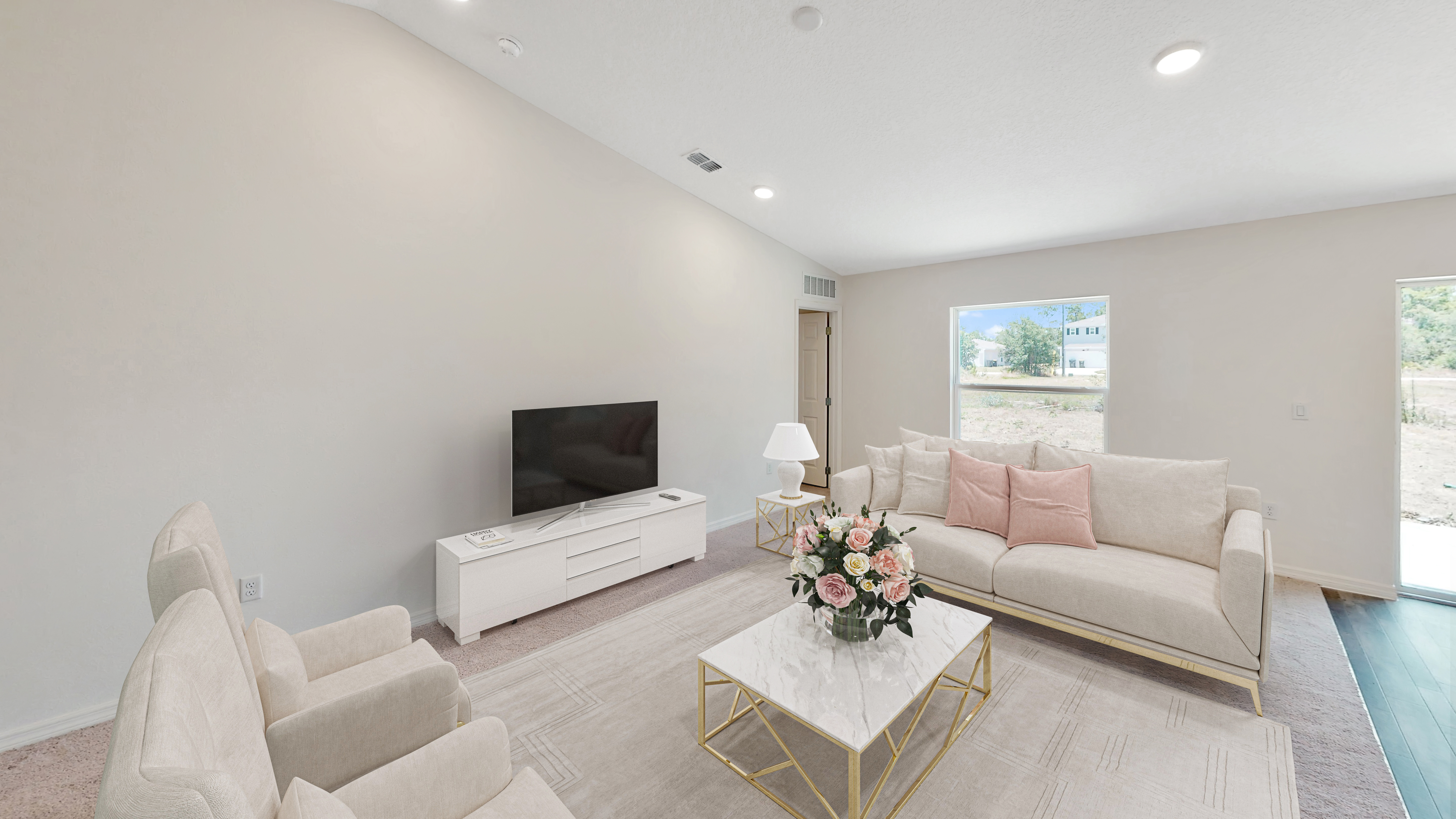 Modern living room interior with beige sofas, a TV, and a coffee table with a floral centerpiece.