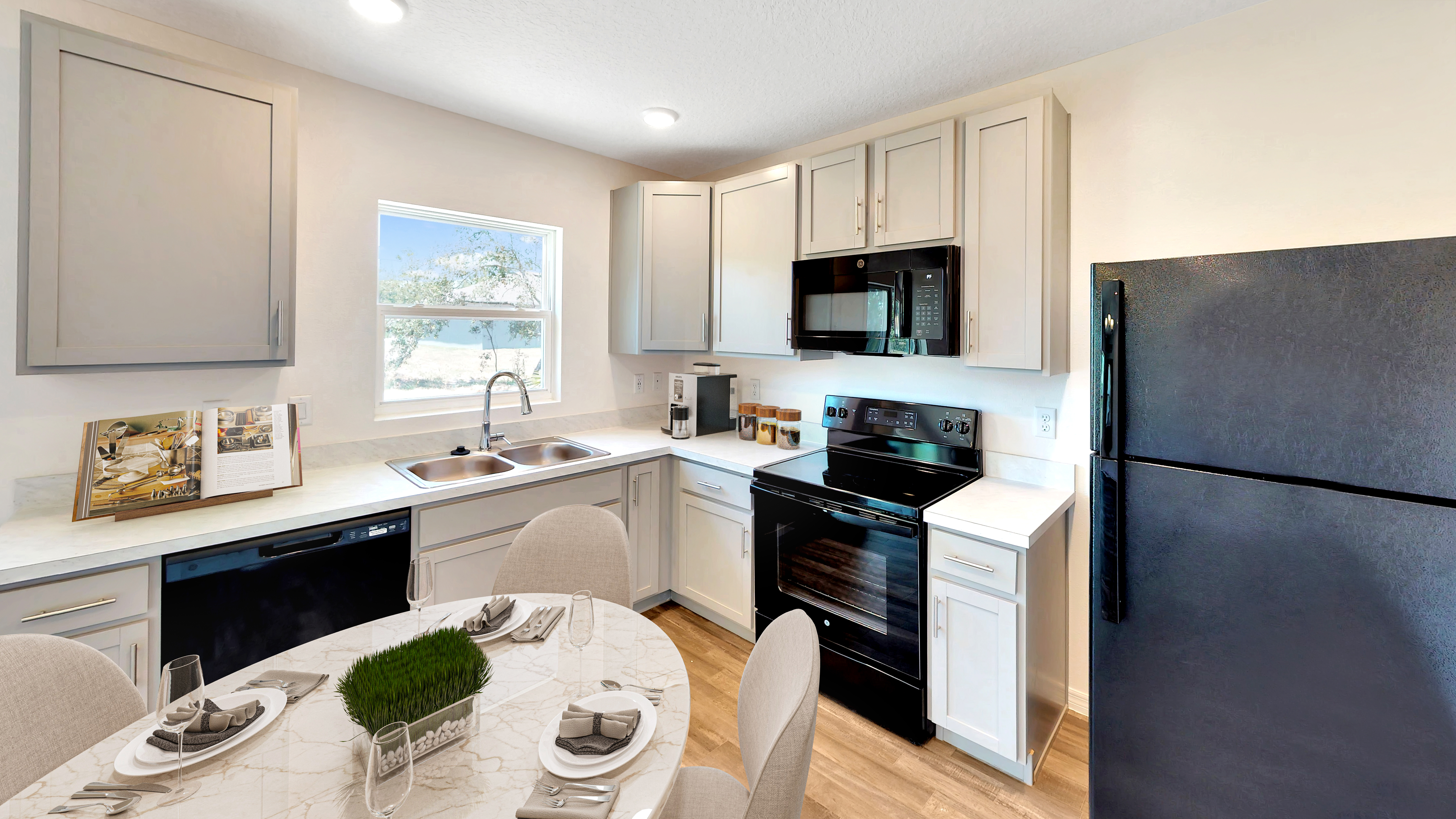 Modern kitchen with light cabinetry, black appliances, and a marble dining table set for four.