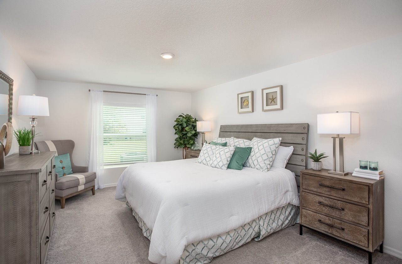 Modern bedroom with a cozy white bed, wooden furniture, and soft natural lighting.