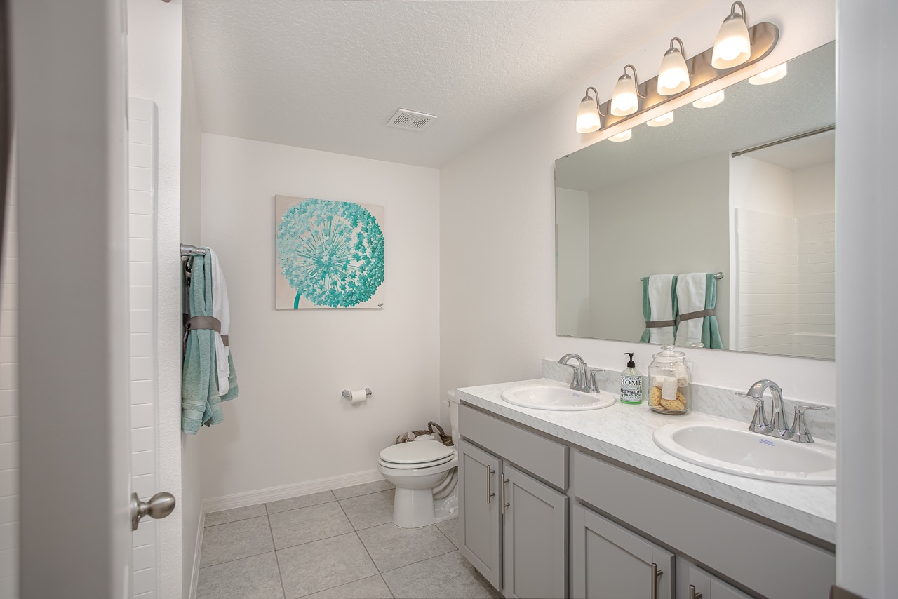 Modern bathroom featuring double vanity with large mirror, elegant lighting, and minimalist decor in neutral tones.
