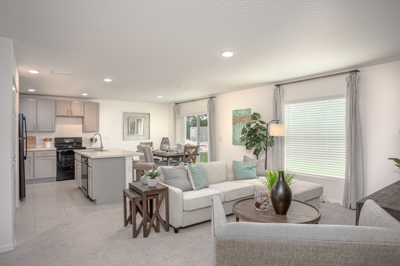 Modern open-concept living room and kitchen with neutral decor, featuring a cozy sectional sofa, stylish dining area, and natural light.