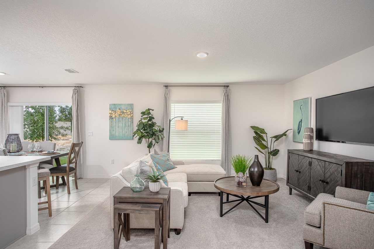 Modern living room with stylish decor, neutral tones, and natural light from a large window.