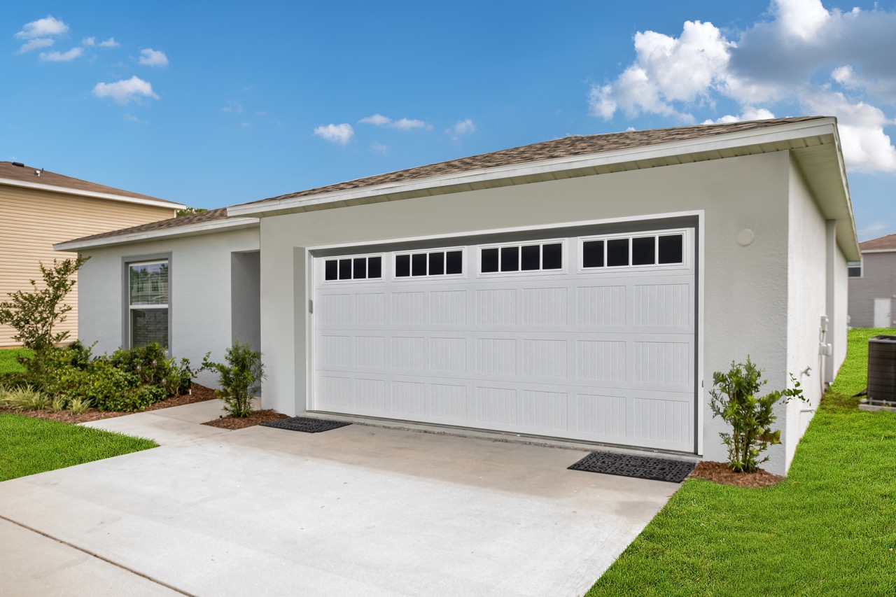 Modern white garage of a suburban home with a neatly maintained lawn and clear blue sky.