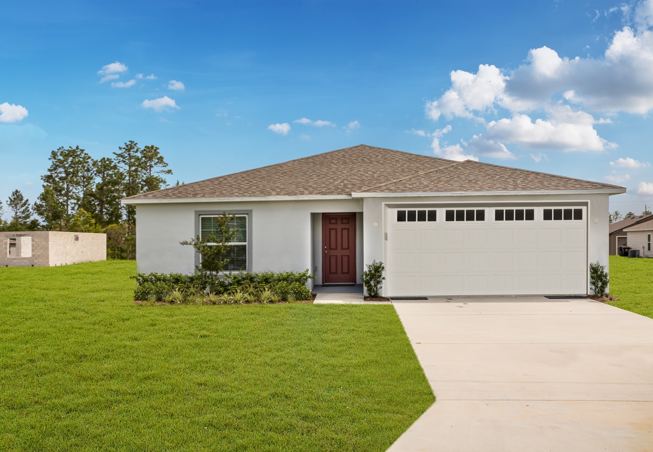 Modern single-story house with attached garage and lush green lawn under a clear blue sky.