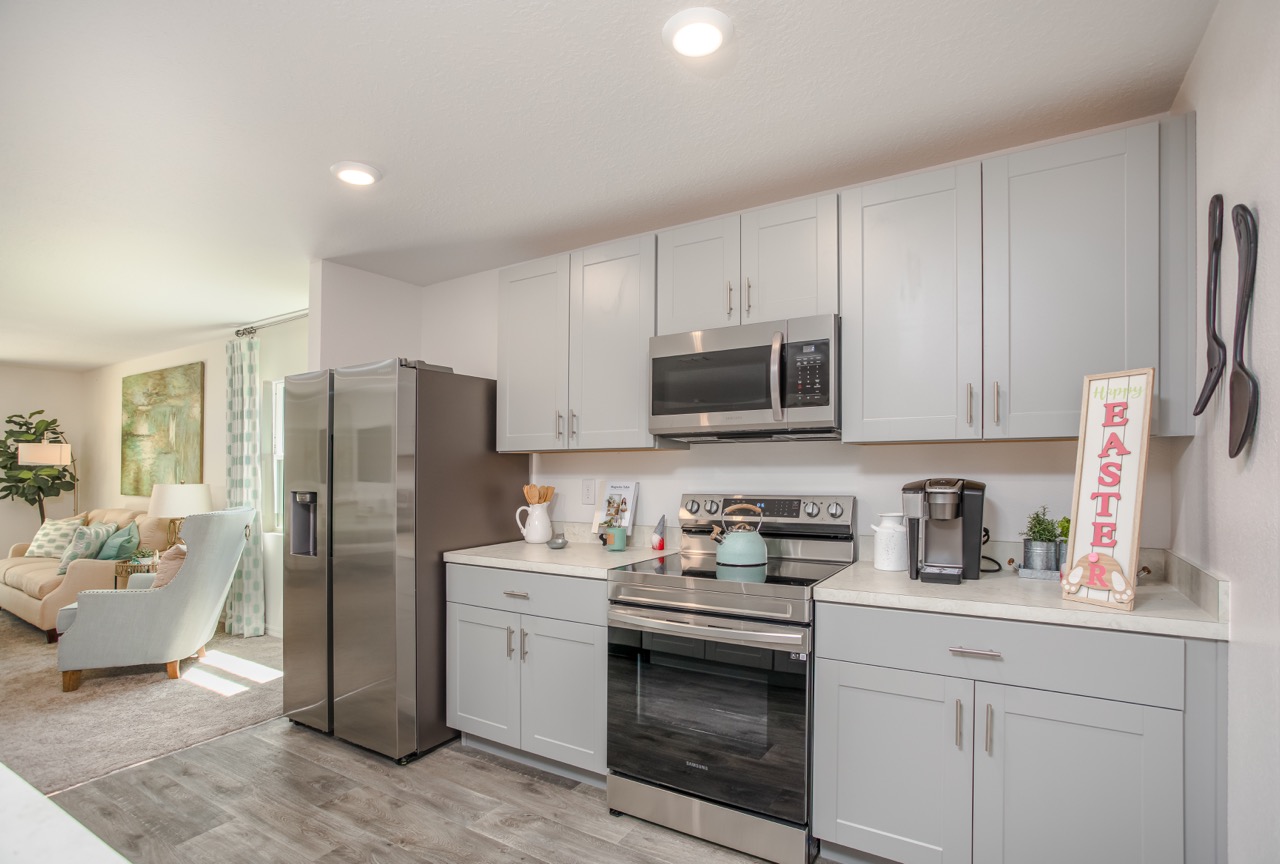 Modern kitchen with stainless steel appliances, light gray cabinets, and Easter decor on the counter.