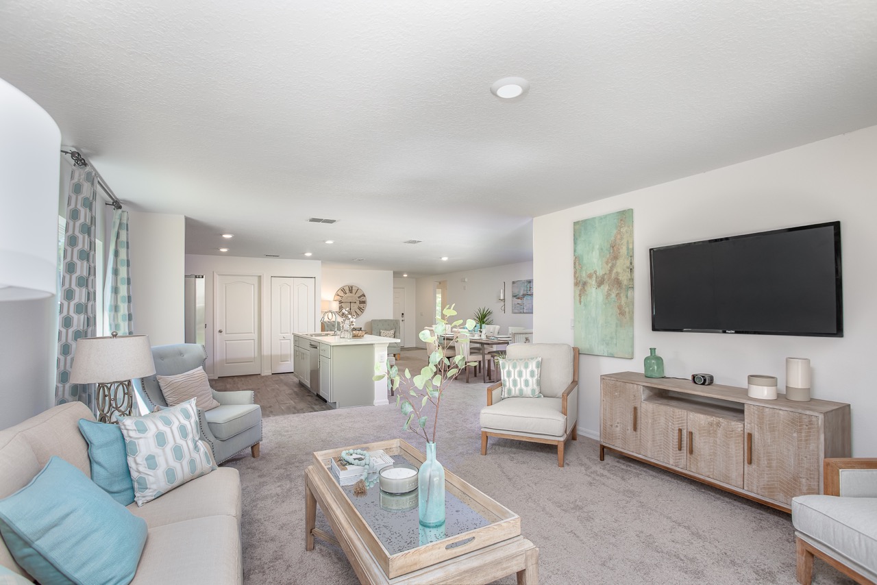 Stylish open-concept living room and kitchen with modern decor, featuring a mounted TV, abstract art, and cozy seating.