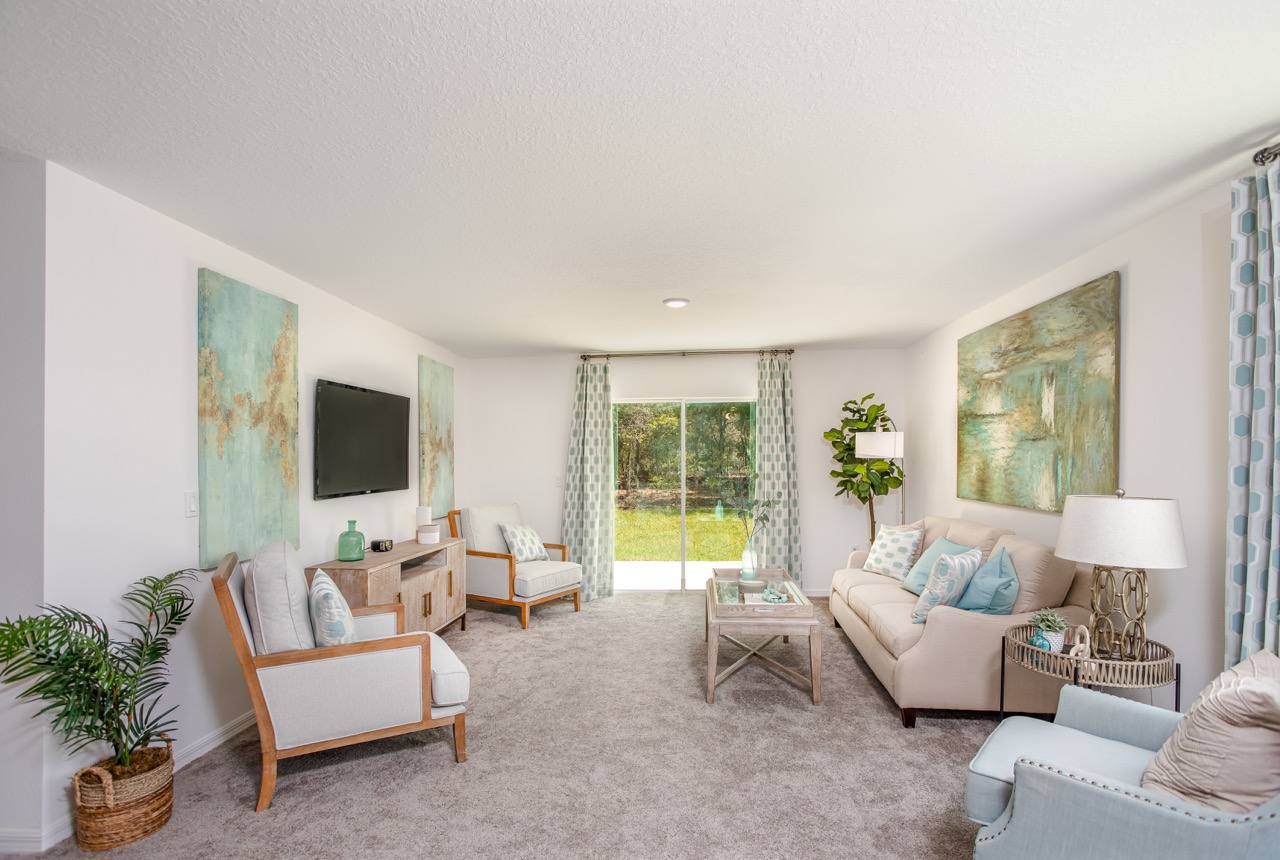 Modern living room with contemporary decor, featuring pastel furniture, abstract wall art, and a large window overlooking a garden.