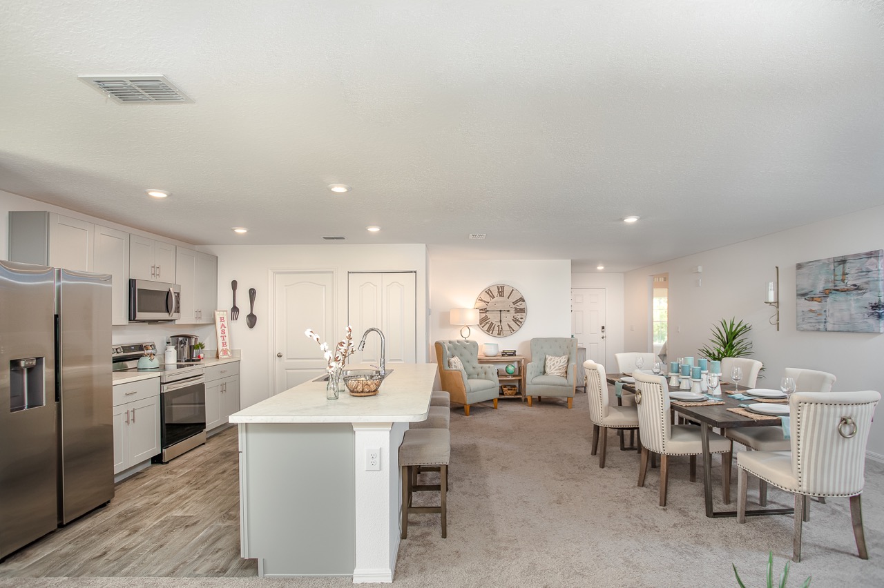 Bright and spacious open-concept kitchen and dining area with modern appliances, island seating, and cozy living space featuring stylish decor.