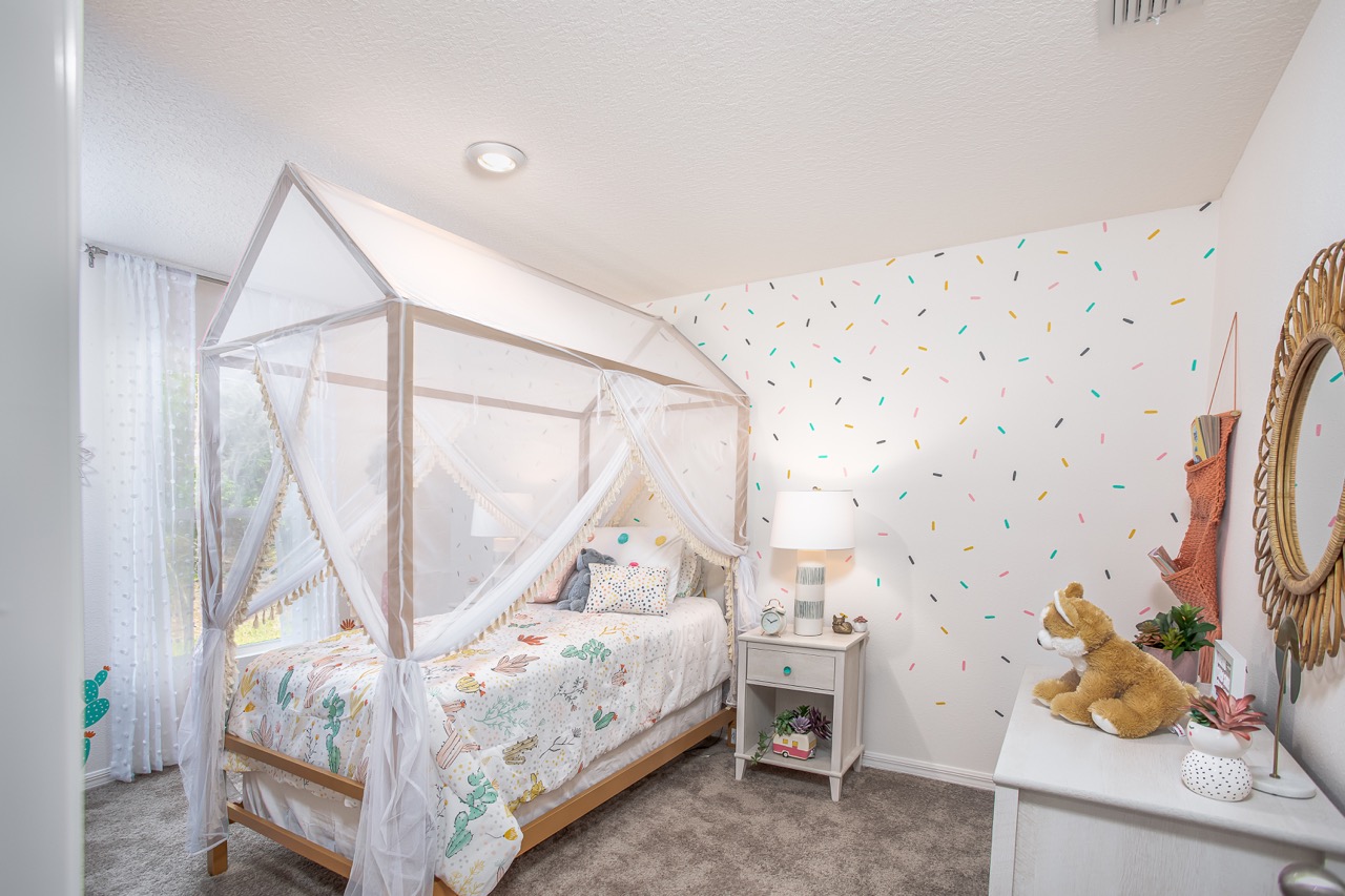 Charming children's bedroom with a house-shaped canopy bed, colorful polka dot wall, and playful decor.