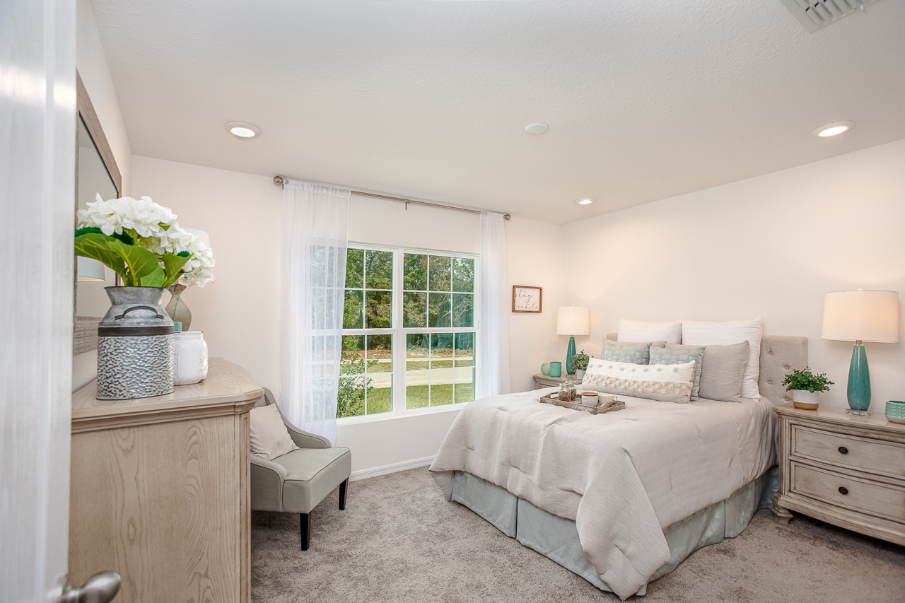 Elegant modern bedroom with neutral tones, large window, and stylish decor elements.