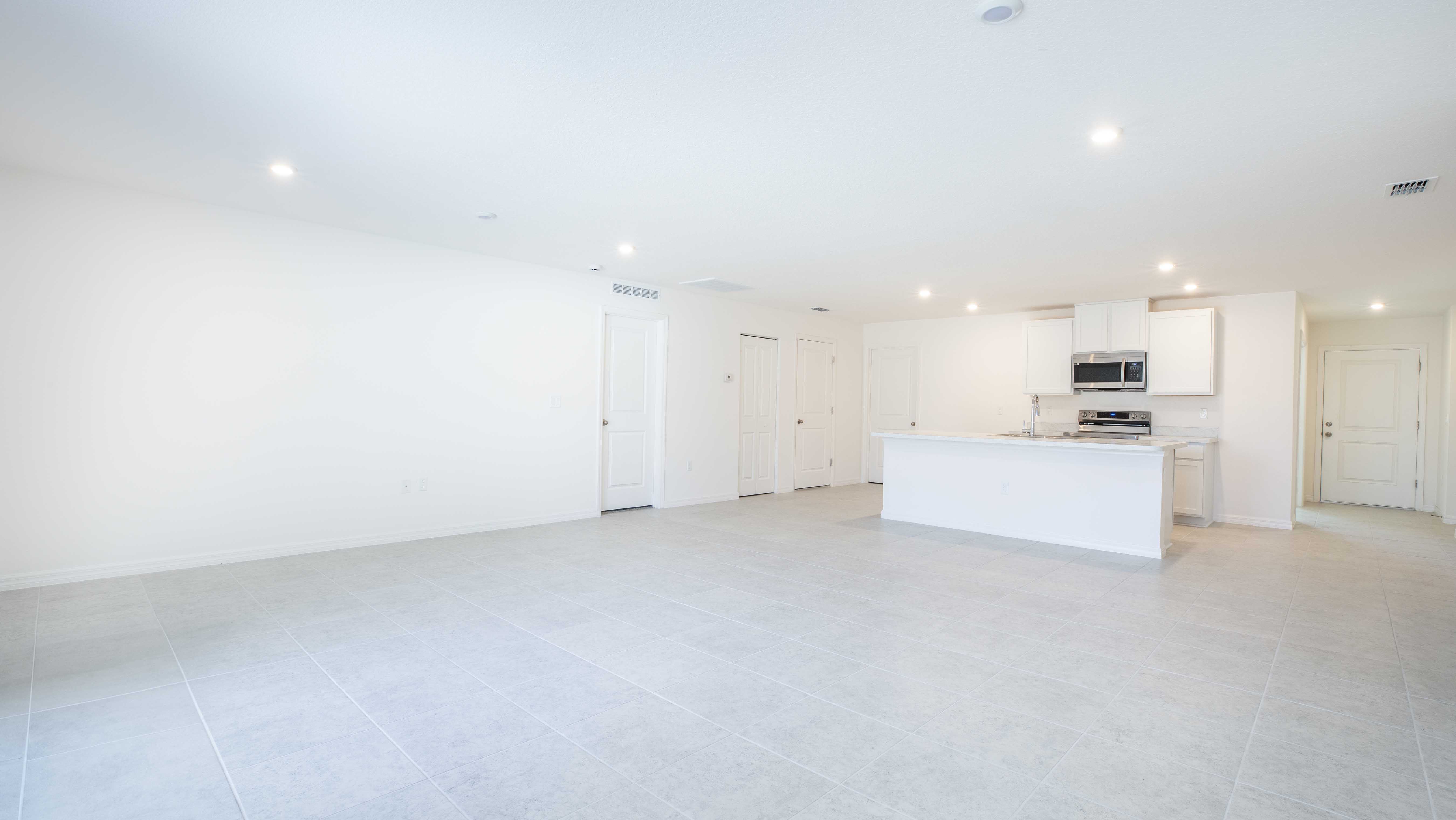 Bright, modern open-concept kitchen and living area with white cabinetry and stainless steel appliances.