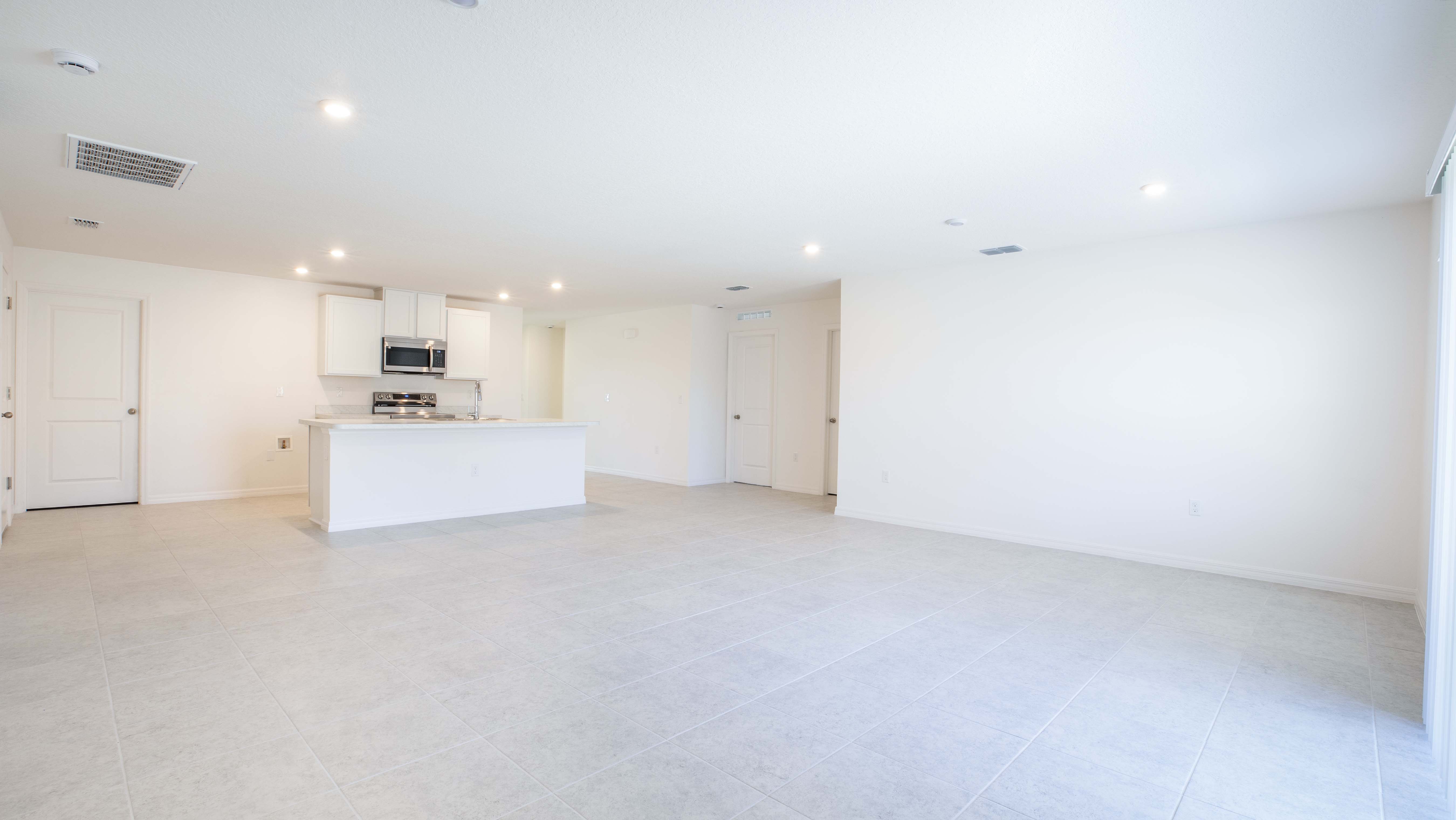 Bright, spacious open-concept kitchen and living area with modern tile flooring and recessed lighting.