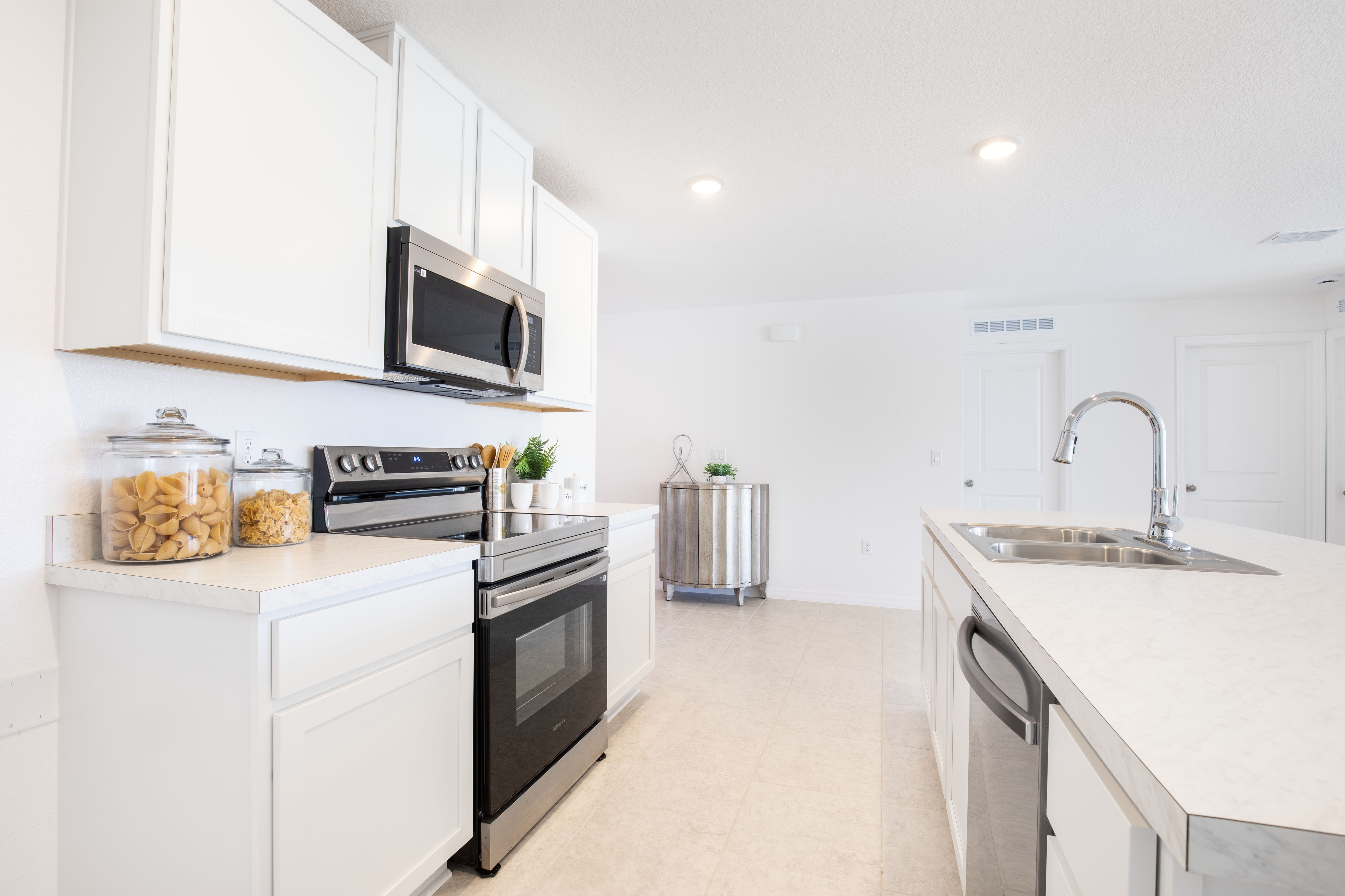 Modern kitchen with white cabinets, stainless steel appliances, and a sleek island featuring a double sink.
