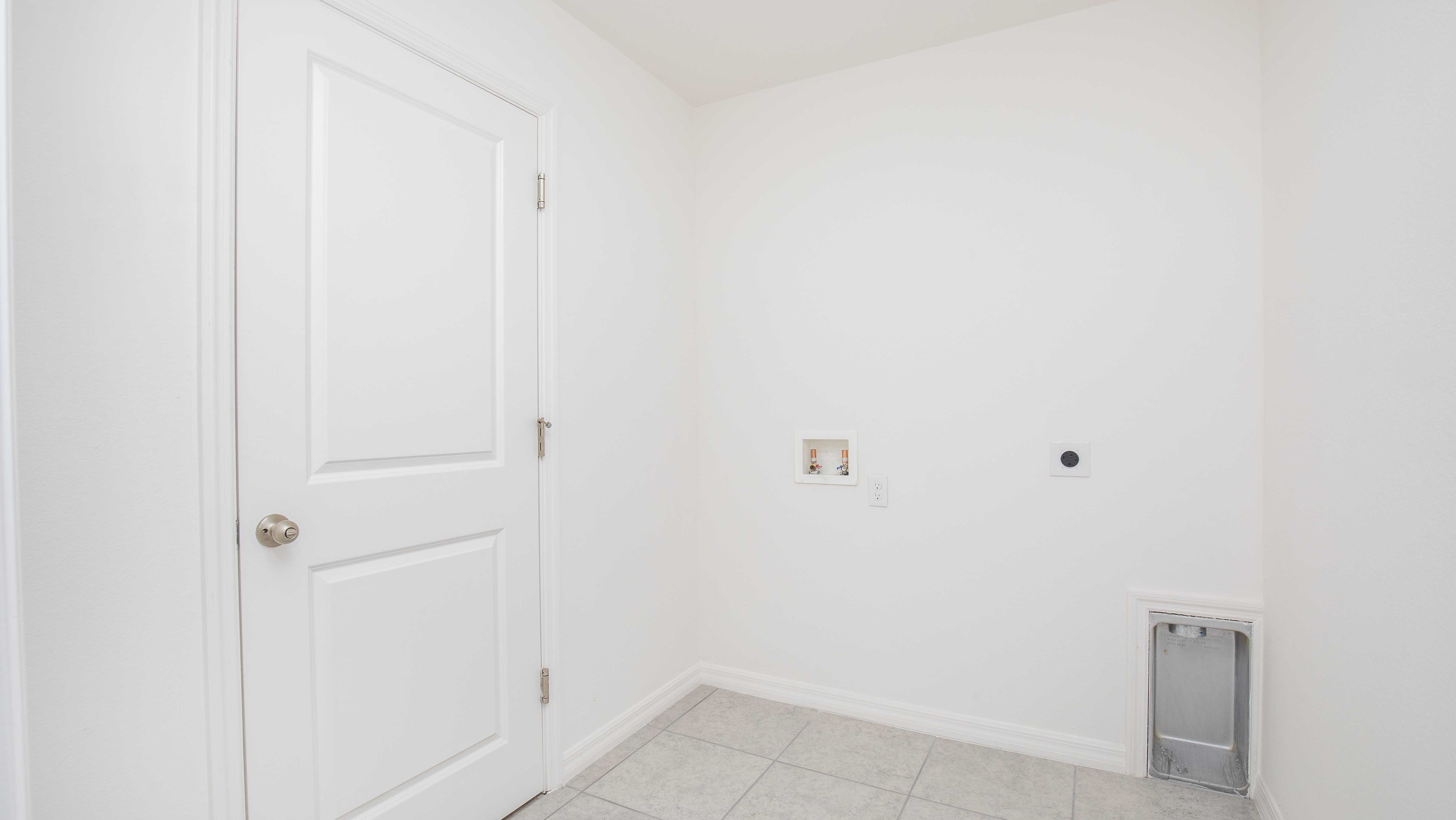 Empty laundry room with white walls, tile flooring, and utility hookups.