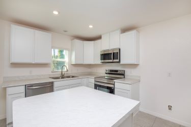 Modern kitchen with white cabinets, stainless steel appliances, and a spacious island countertop.