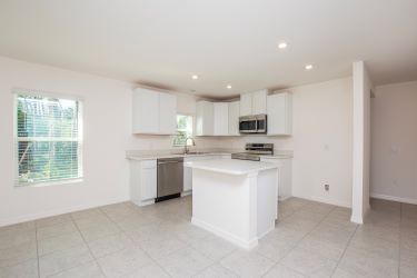 Bright, modern kitchen with white cabinetry, stainless steel appliances, and tile flooring.