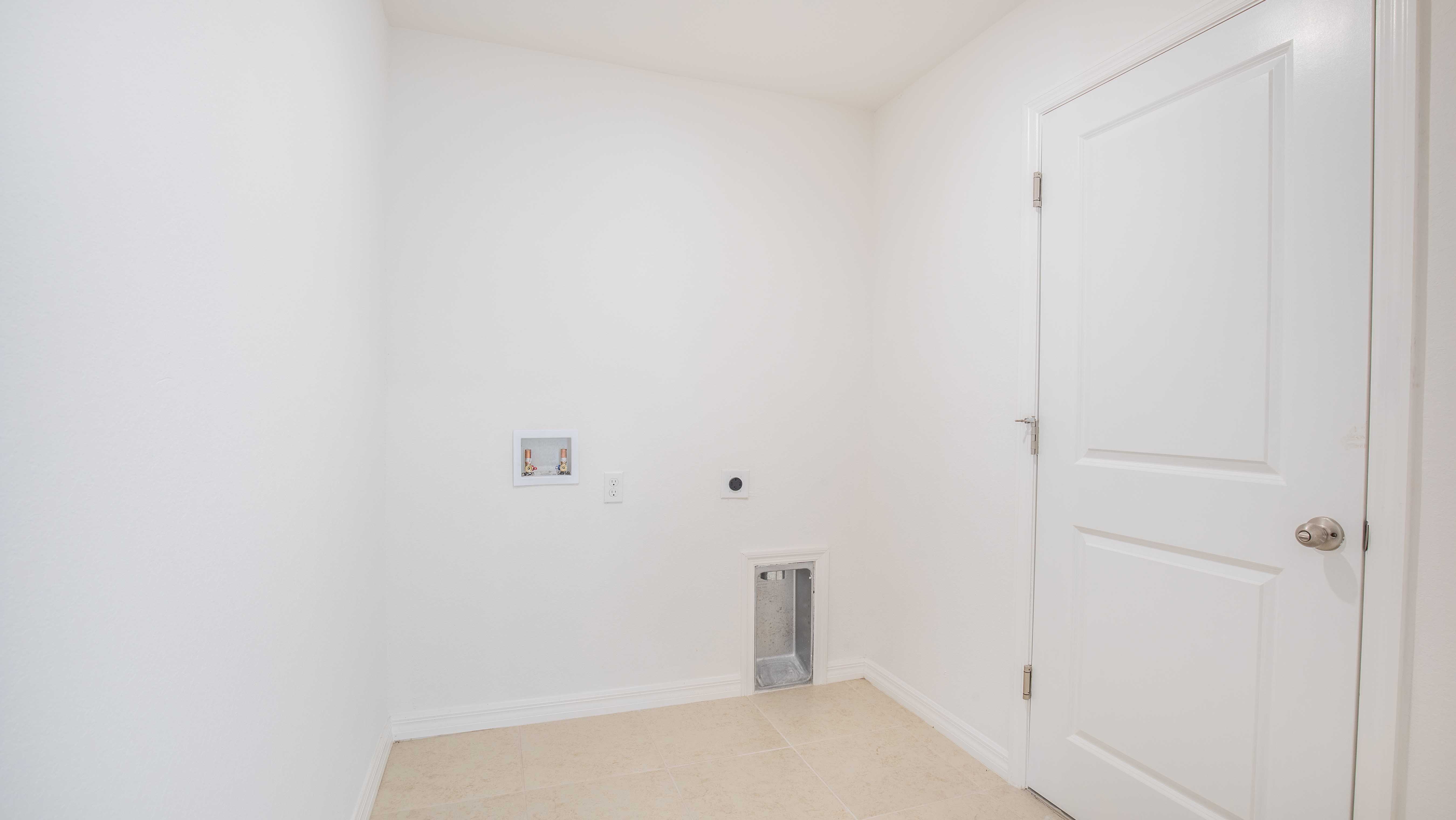 Minimalist laundry room with hookups and white door on tiled floor.