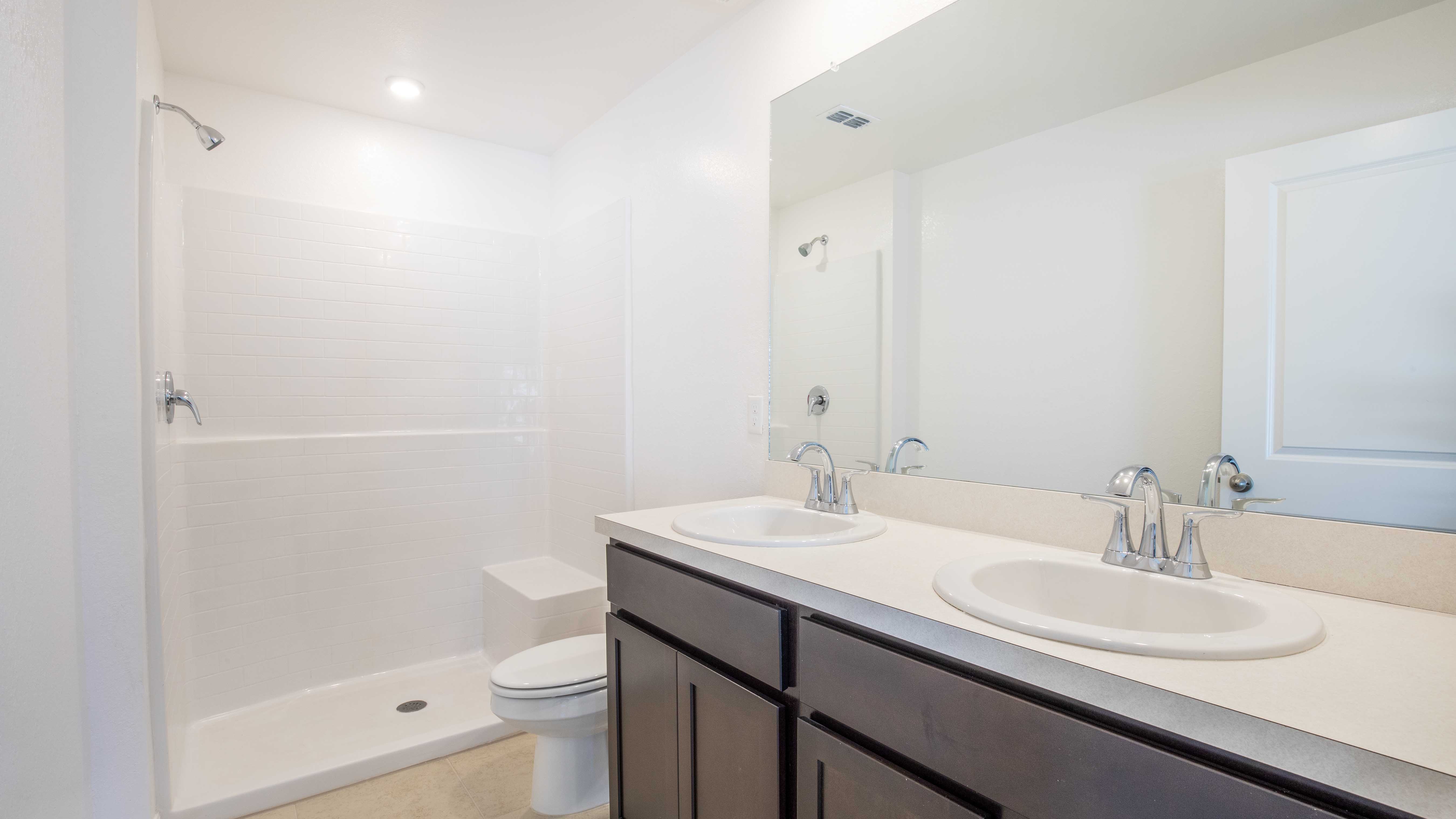 Modern bathroom with a double sink vanity, large mirror, and walk-in shower.