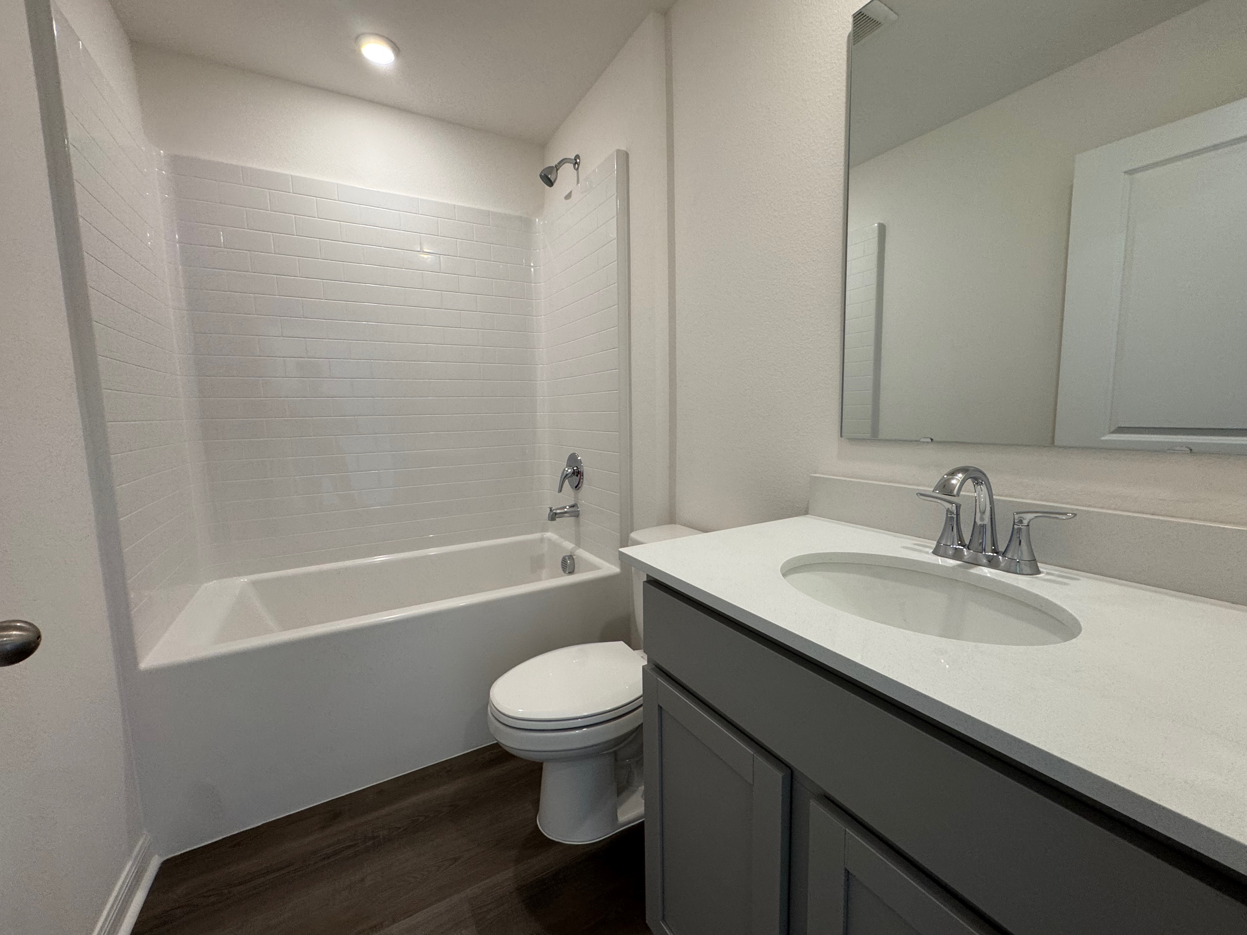 Modern bathroom with white tiled bathtub, sleek vanity, and chrome fixtures.