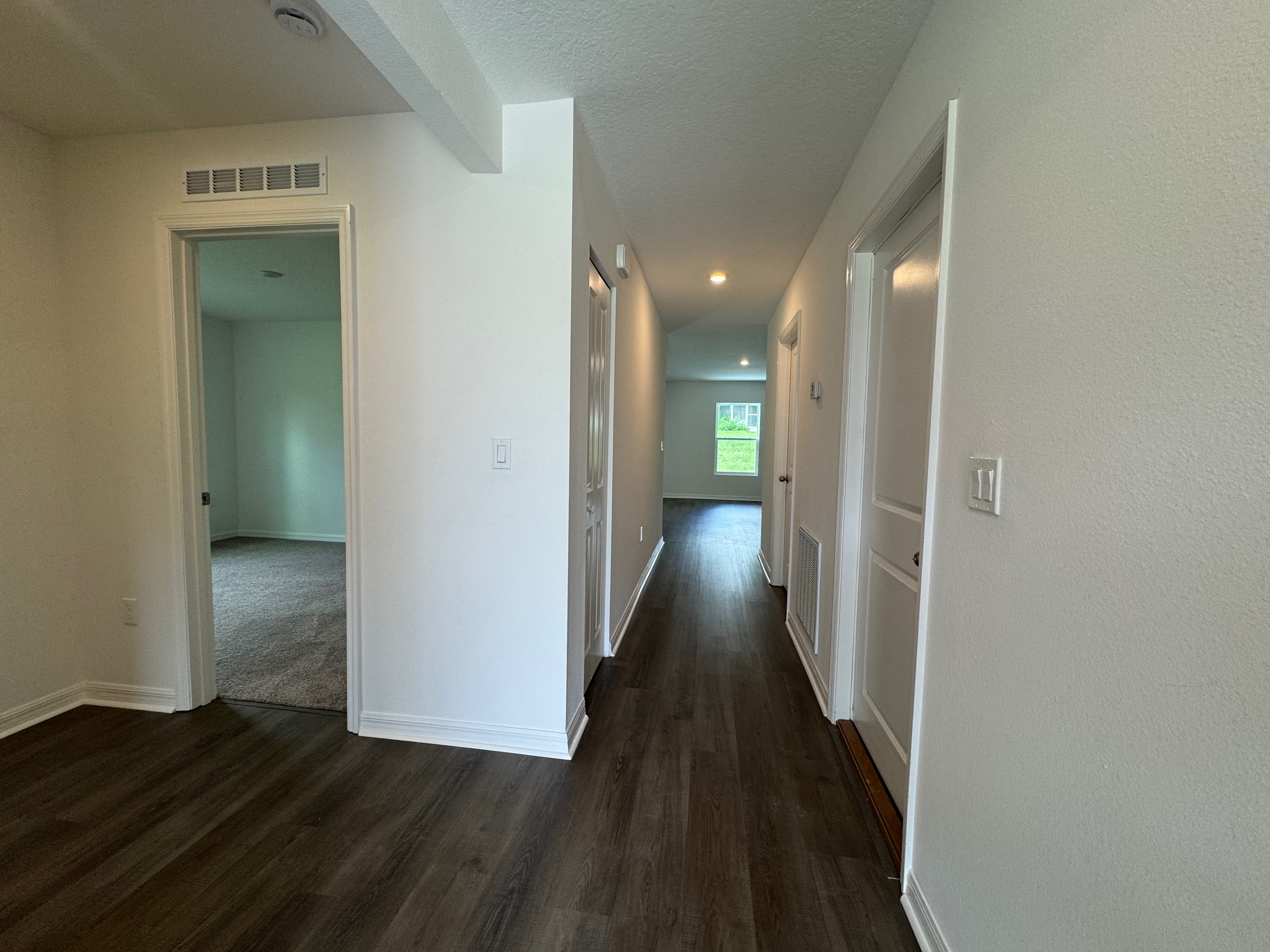 Bright and modern hallway in a home with wood flooring and white walls.