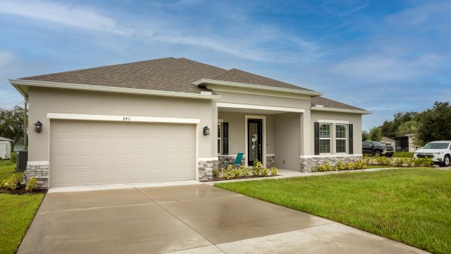 Modern single-story house with a two-car garage and well-maintained yard under a clear blue sky.