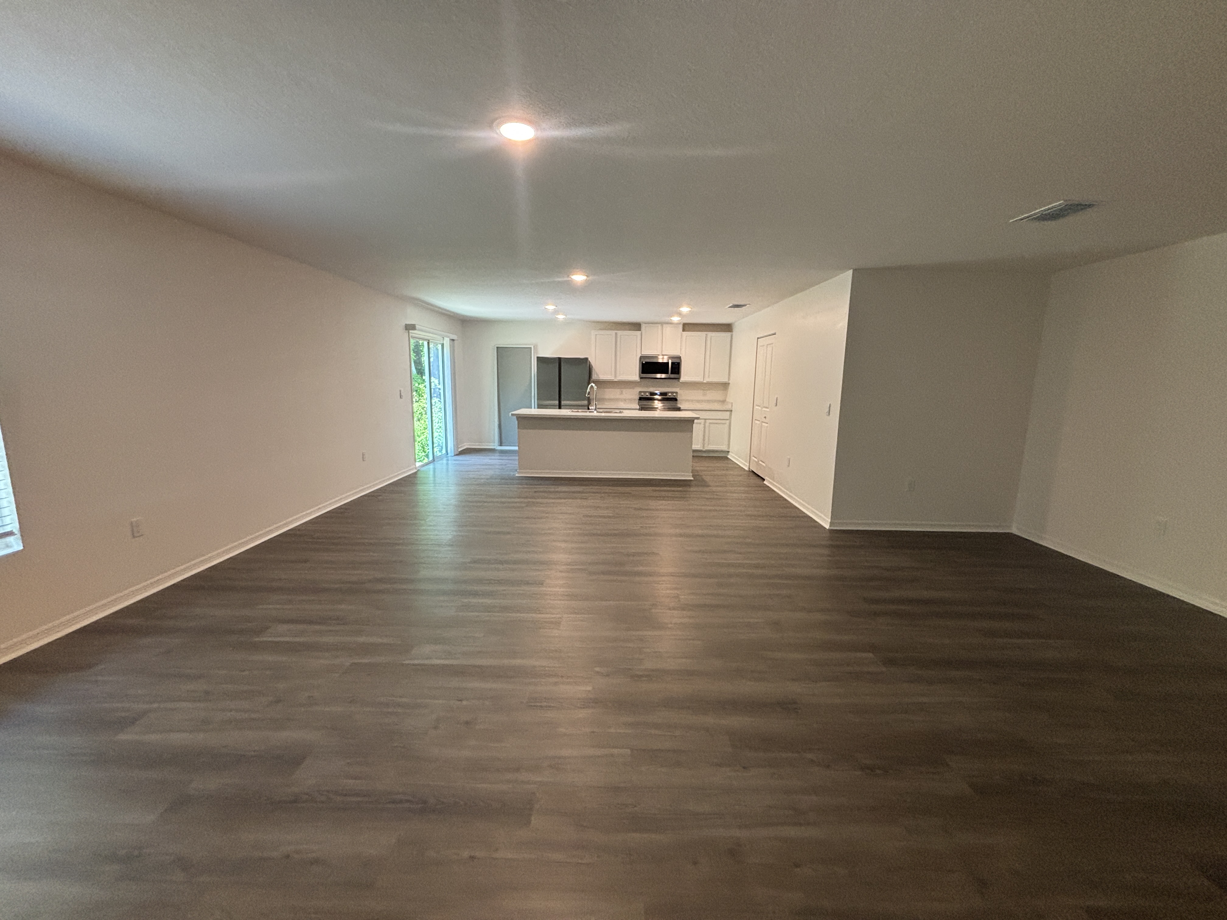 Spacious open-concept kitchen and living area with sleek hardwood flooring and modern lighting.
