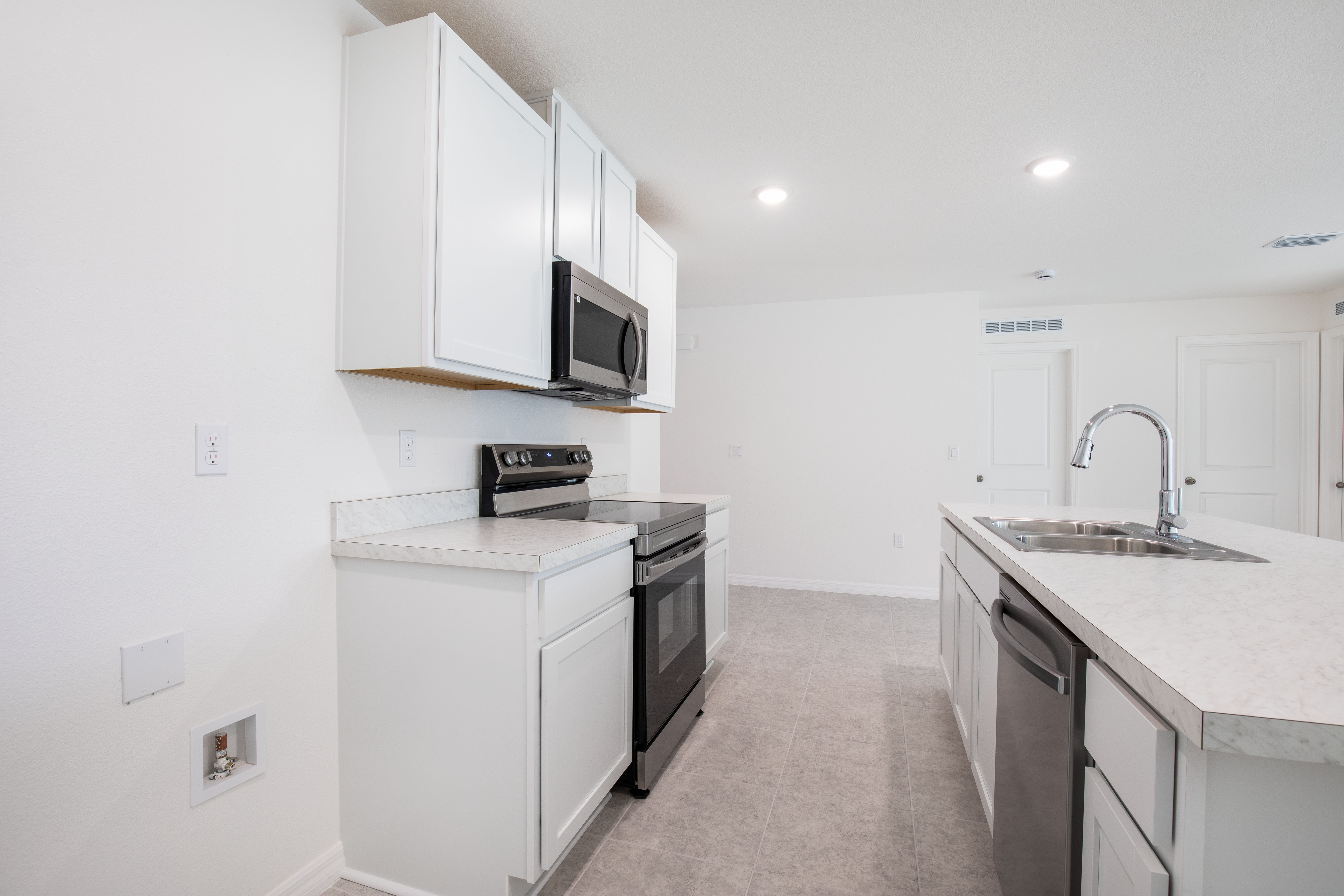 Modern kitchen with white cabinets, stainless steel appliances, and a marble countertop island featuring a built-in sink.